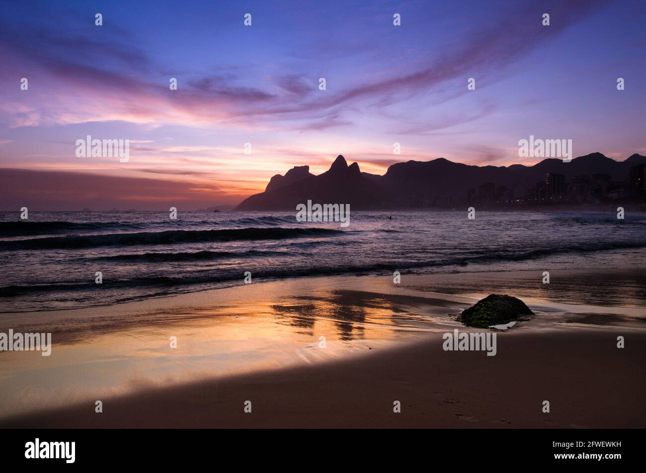 Tramonto sulla spiaggia di Ipanema a Rio de Janeiro, le montagne dell'orizzonte si riflettono nella sabbia bagnata Foto Stock