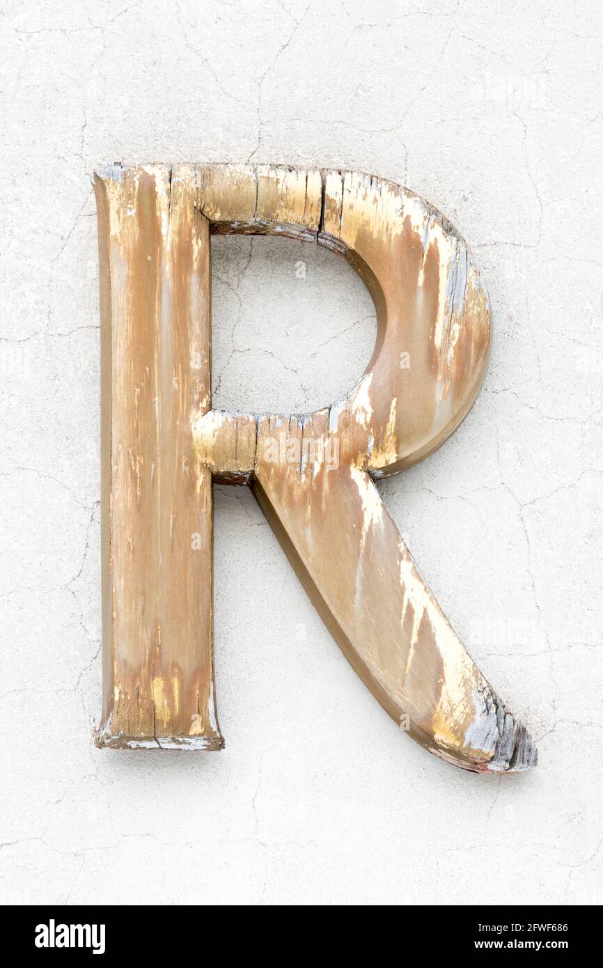Lettera R in legno intemperie di colore dorato Foto Stock
