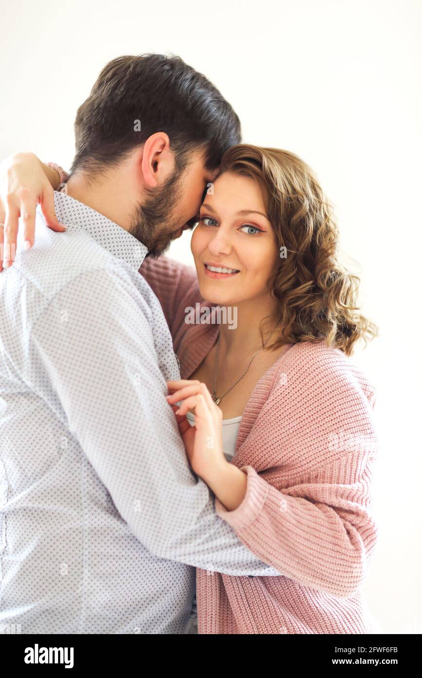 Vista laterale della coppia amorevole del soddisfare abbracciando delicatamente su bianco sfondo a casa Foto Stock