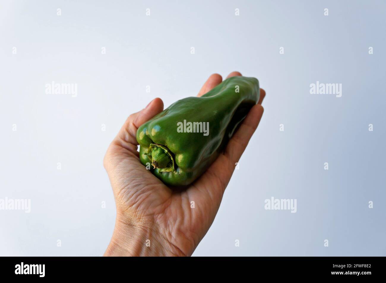 Pepe verde a portata di mano su sfondo luminoso Foto Stock