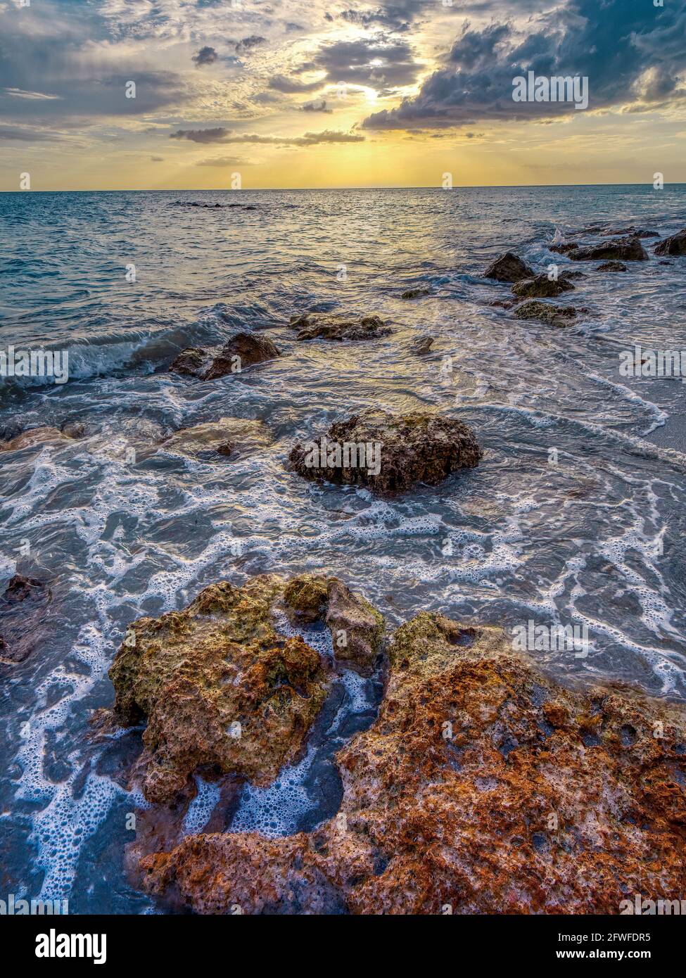 Costa rocciosa di Caspersen Beach a Venezia Florida USA con Un tramonto giallo arancio sul Golfo del Messico Foto Stock