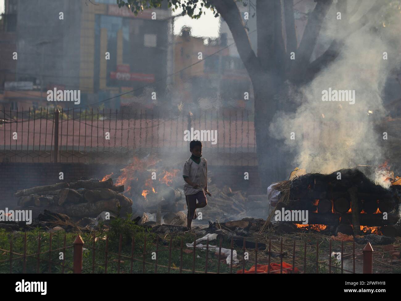 Kathmandu, NE, Nepal. 22 maggio 2021. Un ragazzo attraversa le piri brucianti delle vittime del COVID-19 in un crematorio locale a Kathmandu, capitale nepalese, il 22 maggio 2020. Credit: Aryan Dhimal/ZUMA Wire/Alamy Live News Foto Stock