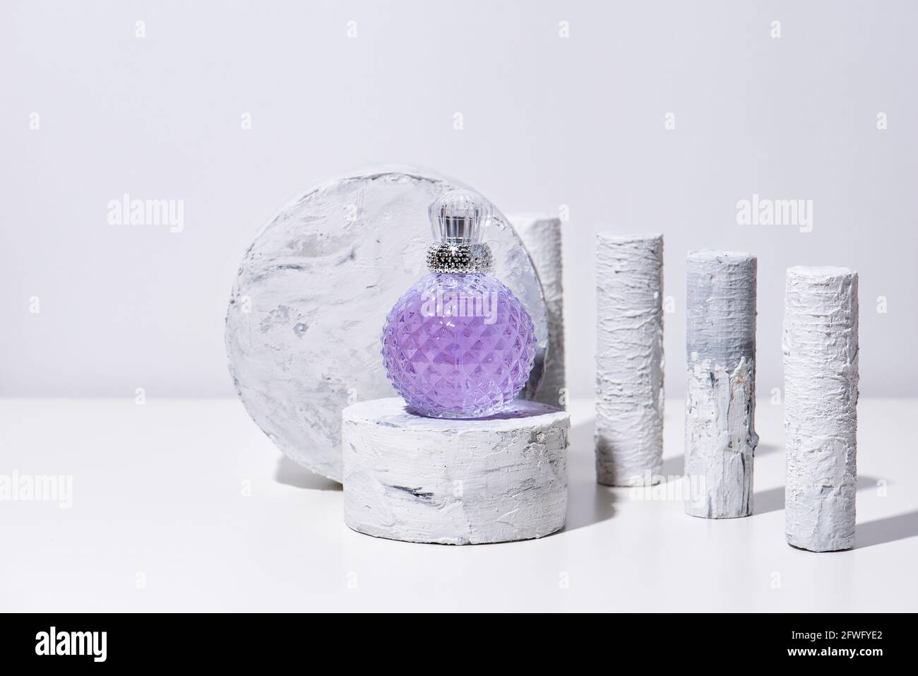 Podio per la presentazione di prodotti in bottiglia di profumo per la pubblicità e l'imballaggio. Piedistallo di bellezza naturale con finiture in marmo e luce solare su sfondo bianco Foto Stock