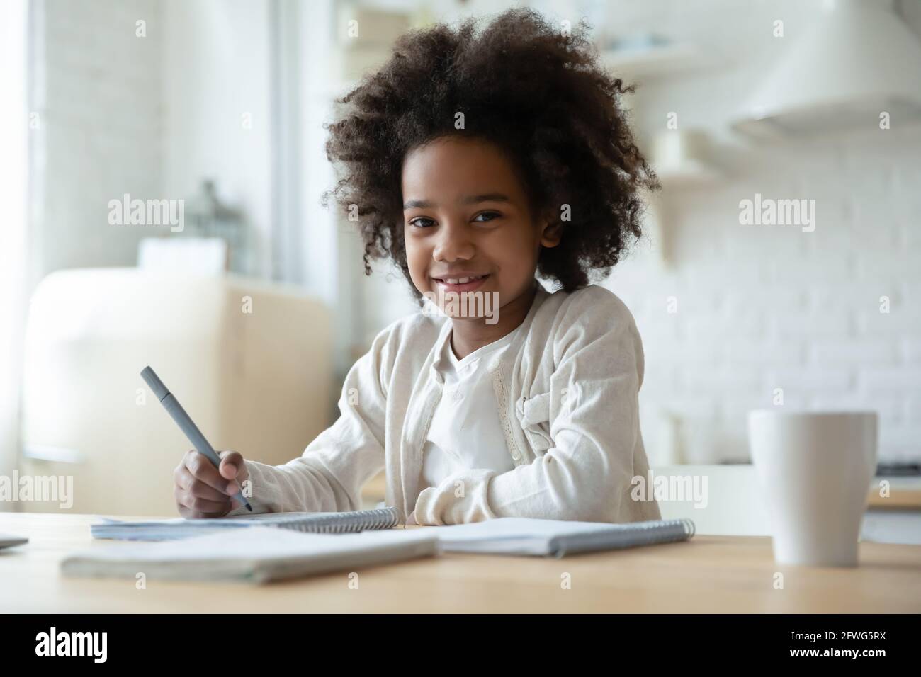 Ritratto di ragazza biraciale felice fare lavoro a casa Foto Stock