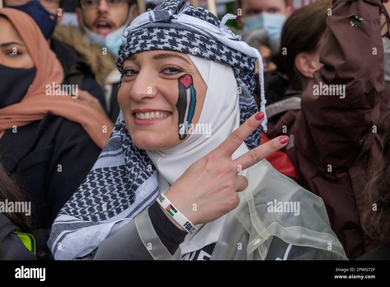 Londra, Regno Unito. 22 maggio 2021. Una donna con la bandiera palestinese su una mappa della Palestina sul suo volto fa un segno di vittoria. Migliaia di persone attraversano Londra per sostenere la Palestina chiedendo la libertà per la Palestina e porre fine alla pulizia etnica delle comunità palestinesi, all'occupazione della Palestina e alle leggi sull'apartheid. Dopo gli attacchi israeliani a Gaza che hanno ucciso circa il 250 e ne hanno distrutto gran parte, chiedono un enorme sforzo internazionale per ricostruire Gaza e per giungere a una soluzione pacifica che consenta a Palestina e Israele di vivere in pace ed evitare attacchi futuri. Peter Marshall/Alamy Live News Foto Stock