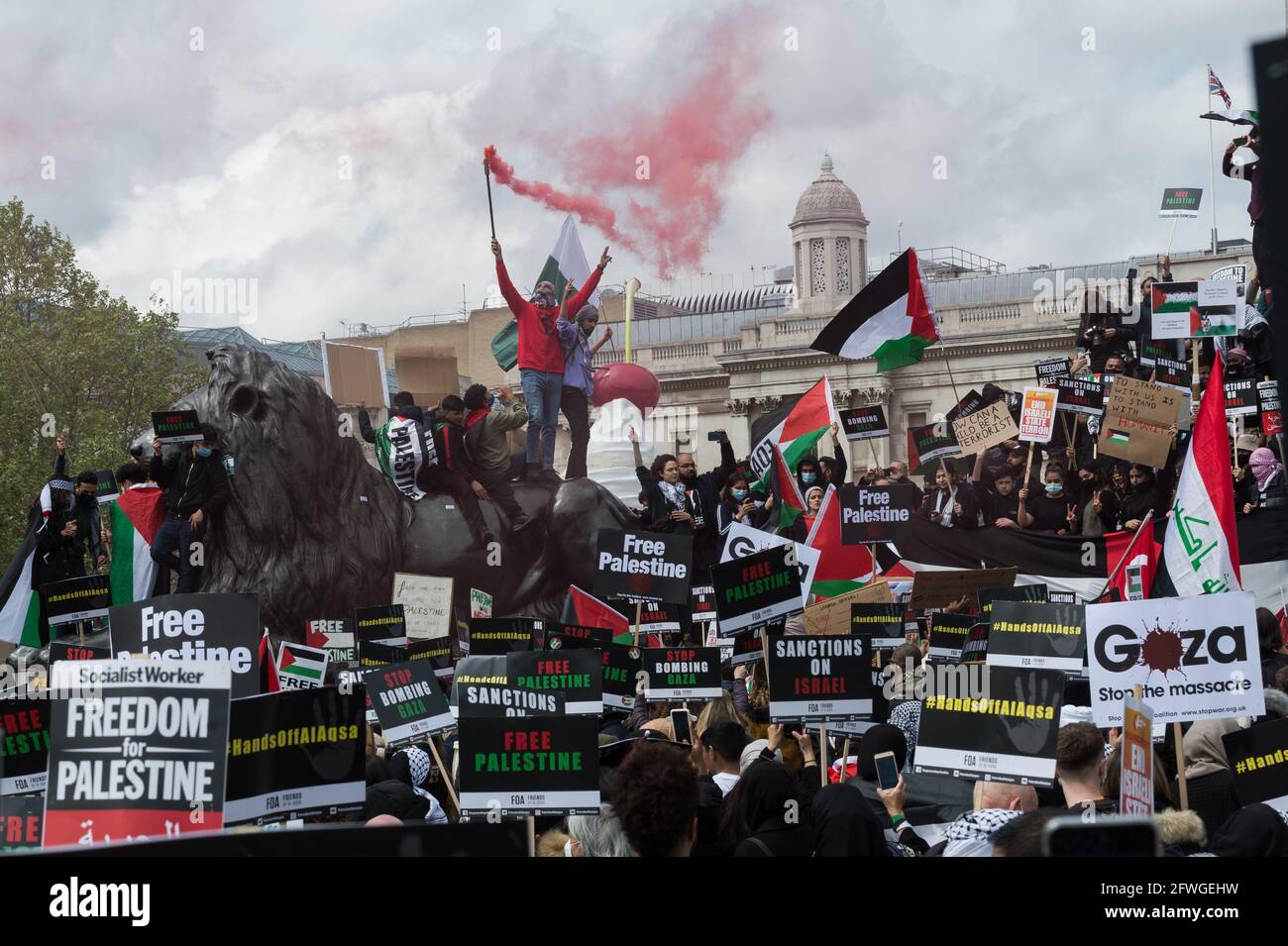 Londra, Regno Unito. 22 maggio 2021. Un dimostratore fa luce sul fumo mentre migliaia di manifestanti si riuniscono in Trafalgar Square nel centro di Londra durante una manifestazione a sostegno della Palestina. Un cessate il fuoco tra Israele e Palestina è entrato in vigore venerdì dopo 11 giorni di scioperi aerei che hanno lasciato più di 250 morti a causa dell'escalation del conflitto per lo sfratto programmato di famiglie palestinesi dalle loro case da parte di coloni ebrei nel distretto di Sheikh Jarrah a Gerusalemme est e scontri con la sicurezza Forze intorno alla città vecchia durante Ramadan. Credit: Wiktor Szymanowicz/Alamy Live News Foto Stock