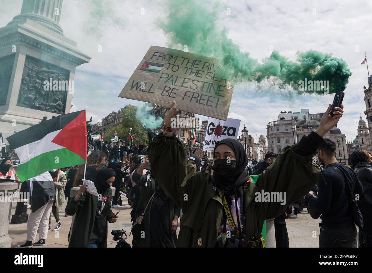 Londra, Regno Unito. 22 maggio 2021. Un dimostratore fa luce sul fumo mentre migliaia di manifestanti si riuniscono in Trafalgar Square nel centro di Londra durante una manifestazione a sostegno della Palestina. Un cessate il fuoco tra Israele e Palestina è entrato in vigore venerdì dopo 11 giorni di scioperi aerei che hanno lasciato più di 250 morti a causa dell'escalation del conflitto per lo sfratto programmato di famiglie palestinesi dalle loro case da parte di coloni ebrei nel distretto di Sheikh Jarrah a Gerusalemme est e scontri con la sicurezza Forze intorno alla città vecchia durante Ramadan. Credit: Wiktor Szymanowicz/Alamy Live News Foto Stock