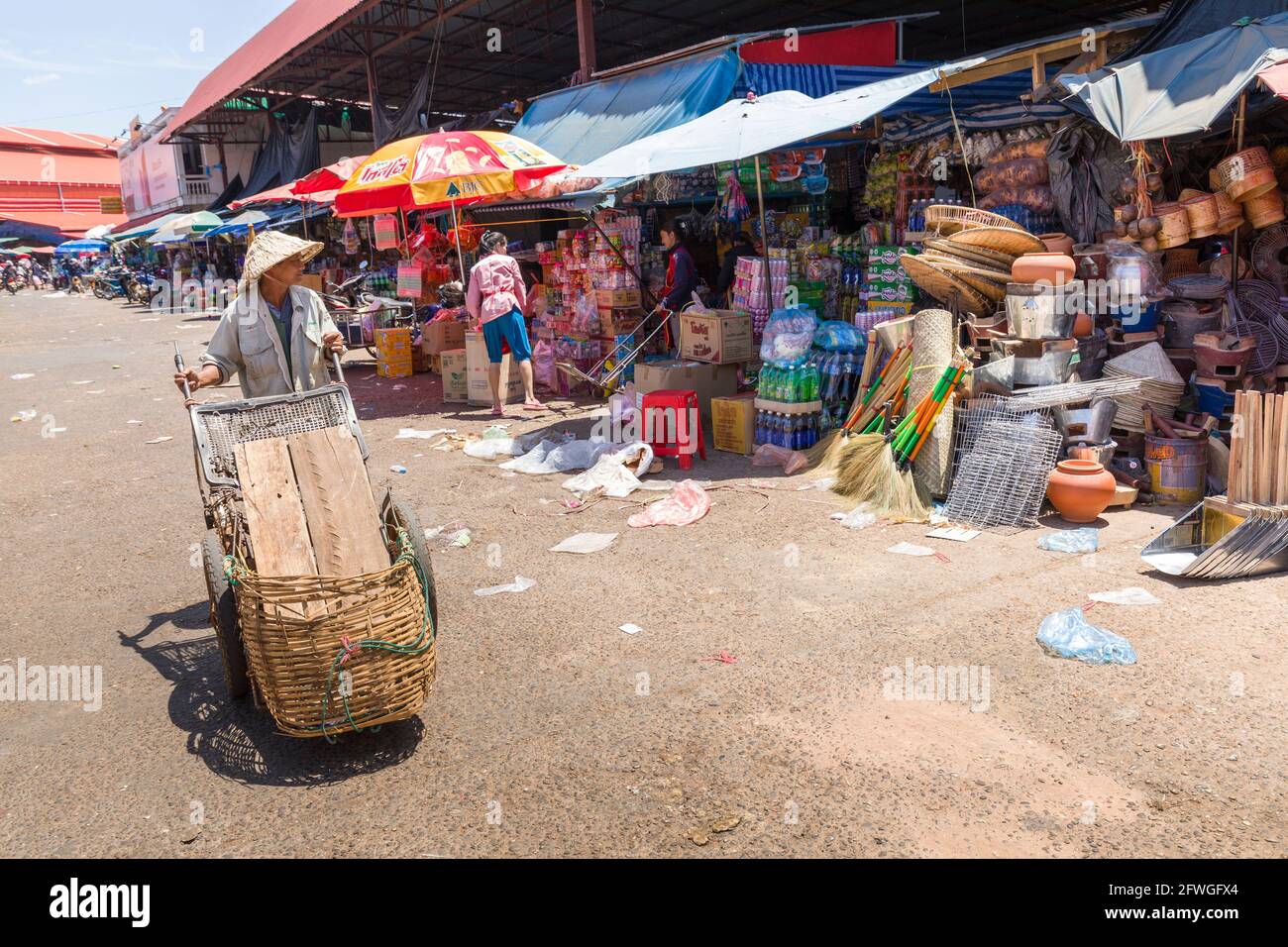 Uomo che ruota barrowt attraverso il mercato all'aperto, Pakse, Laos Foto Stock