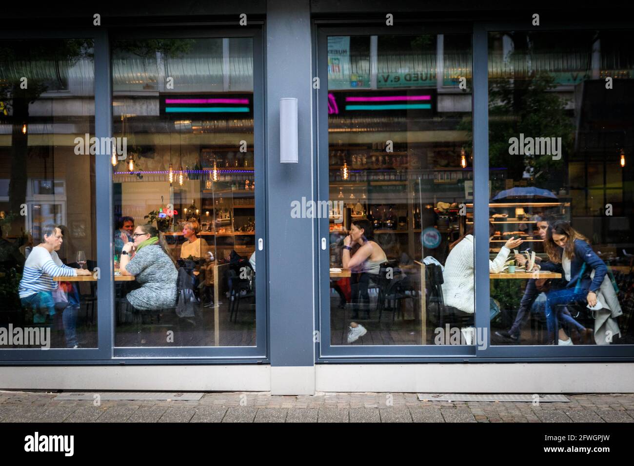 Münster, NRW, Germania. 22 maggio 2021. Le persone godono del loro cibo e bevande al coperto. Le folle si riuniscono nel centro storico di Münster, nonostante la pioggia battente, poiché diventa la prima città del Nord Reno-Westfalia ad essere autorizzata ad aprire bevande e ristoranti al coperto (con test o vaccinazione negativi), e lo shopping senza un test o appuntamento (ma i numeri sono limitati). Münster attualmente ha uno dei più bassi tassi di incidenza di covid in NRW a 17/100k ed è diventato una 'regione del model' per provare la lenta riapertura dei luoghi di ospitalità. Credit: Imageplotter/Alamy Live News Foto Stock