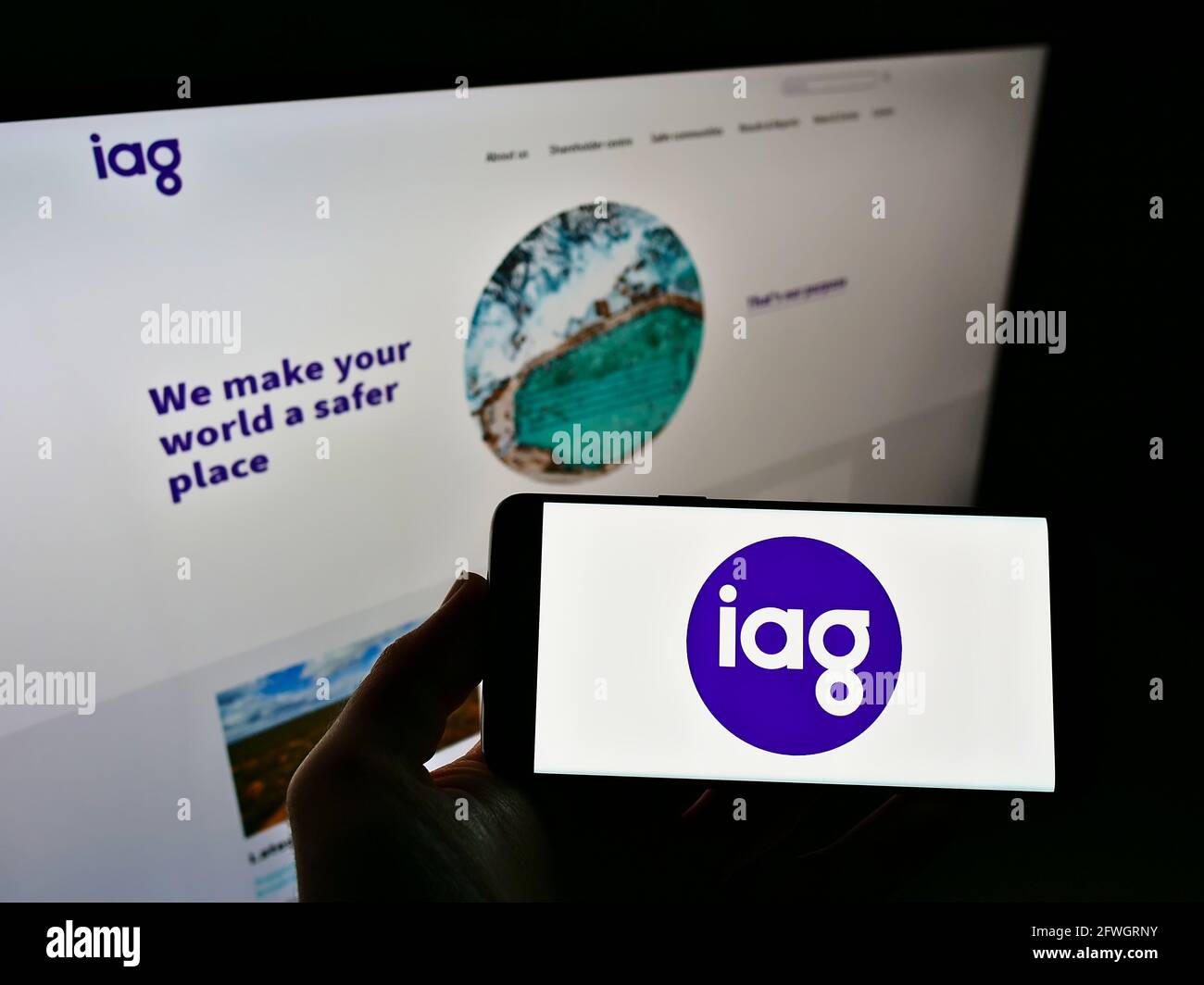 Persona in possesso di smartphone con il logo della società Insurance Australia Group Limited (IAG) sullo schermo davanti al sito Web. Mettere a fuoco il display del telefono. Foto Stock