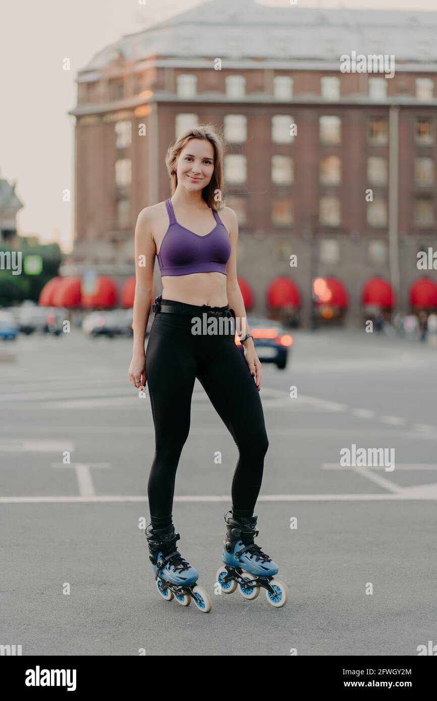 La donna sottile indossa il top corto e i pantaloni si pongono sui rulli  gode di tempo libero ha corpo sano gode rollerblading pose all'aperto  contro urban Foto stock - Alamy