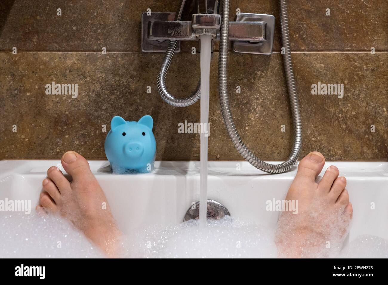 acqua che versa nella vasca da bagno e in una banca di porcellini, concetto di costi e spreco di acqua pulita Foto Stock