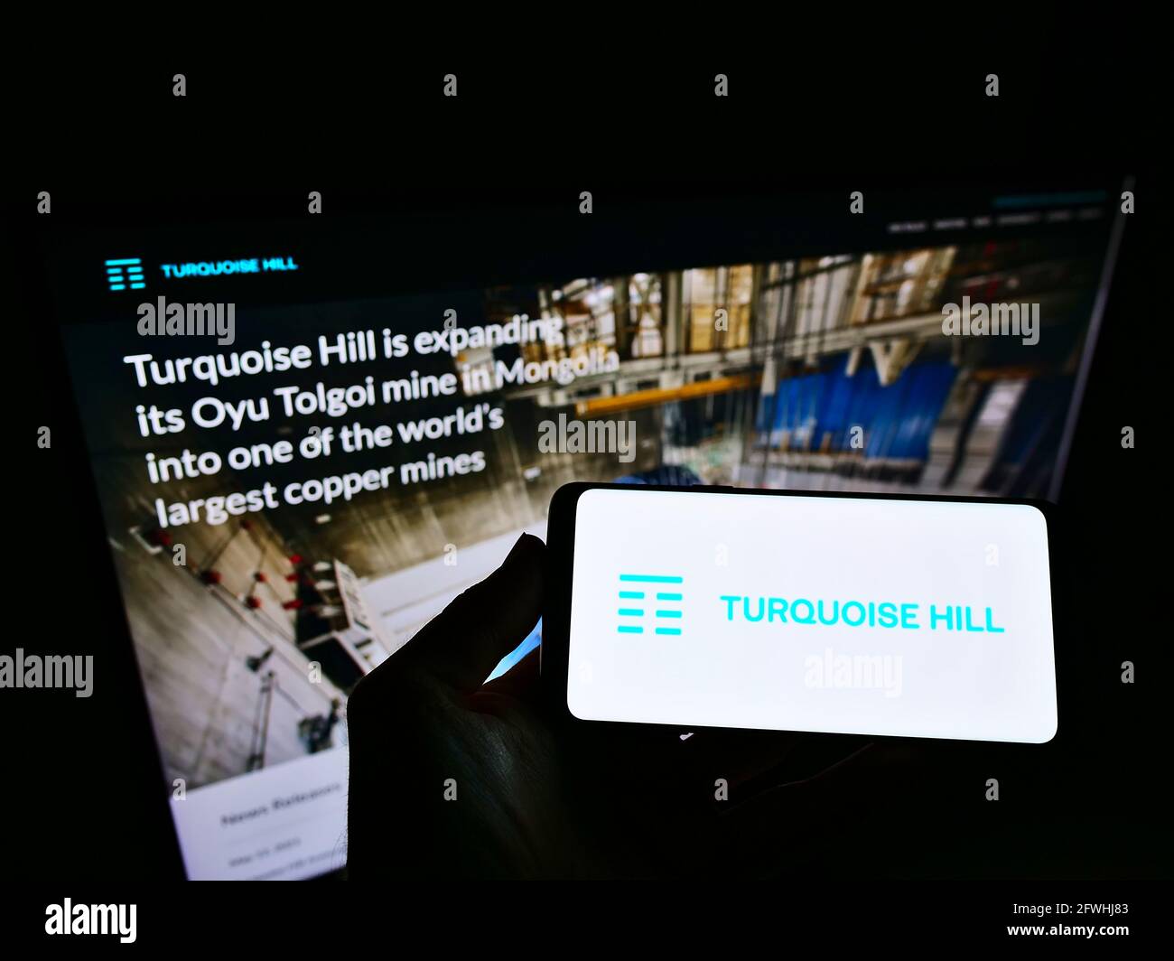 Persona che tiene smartphone con il logo della società mineraria canadese Turquoise Hill Resources Ltd sullo schermo di fronte al sito web. Mettere a fuoco il display del telefono. Foto Stock