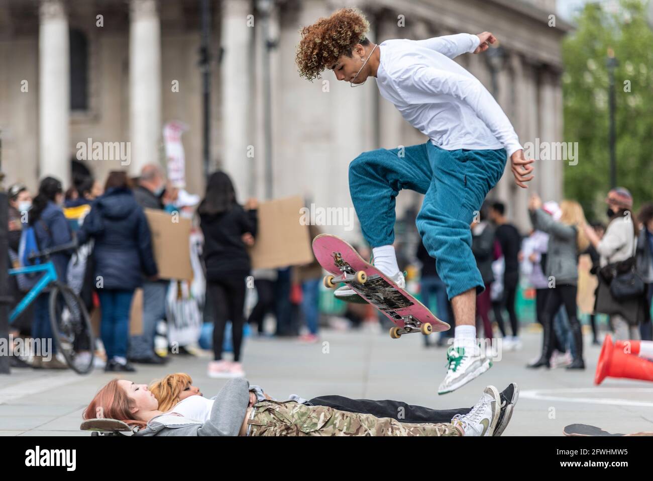 Skateboarders che effettuano acrobazie in strada. Un giovane maschio che salta su due giovani femmine Foto Stock