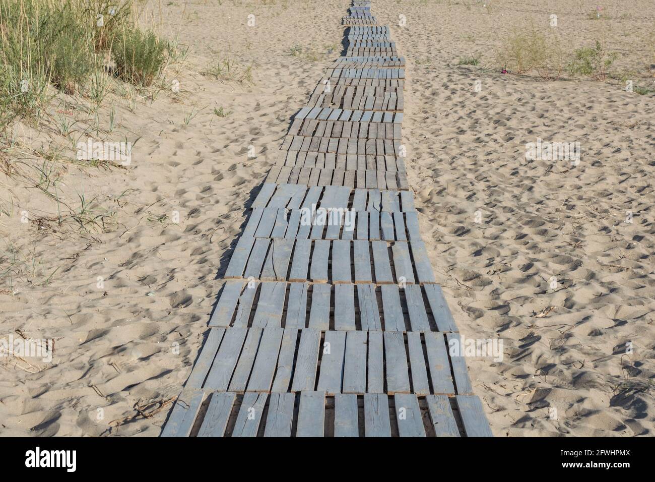 Un percorso tropicale fatto di assi attraverso la spiaggia di sabbia al mare. Foto Stock