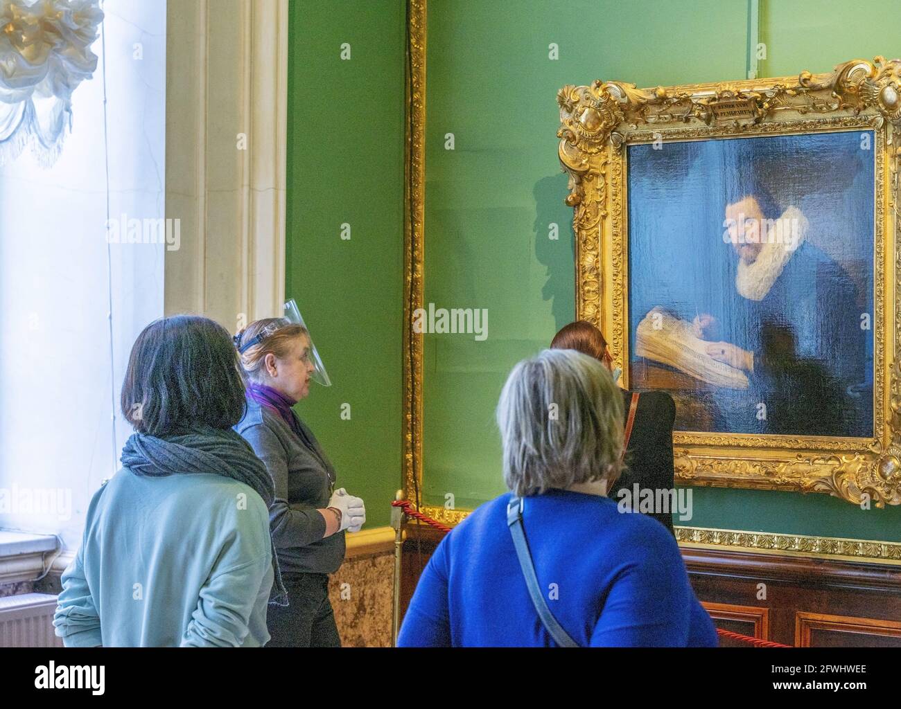 Guida turistica femminile che indossa uno scudo protettivo davanti alla pittura per gruppi di visitatori, Museo Hermitage, Russia Foto Stock