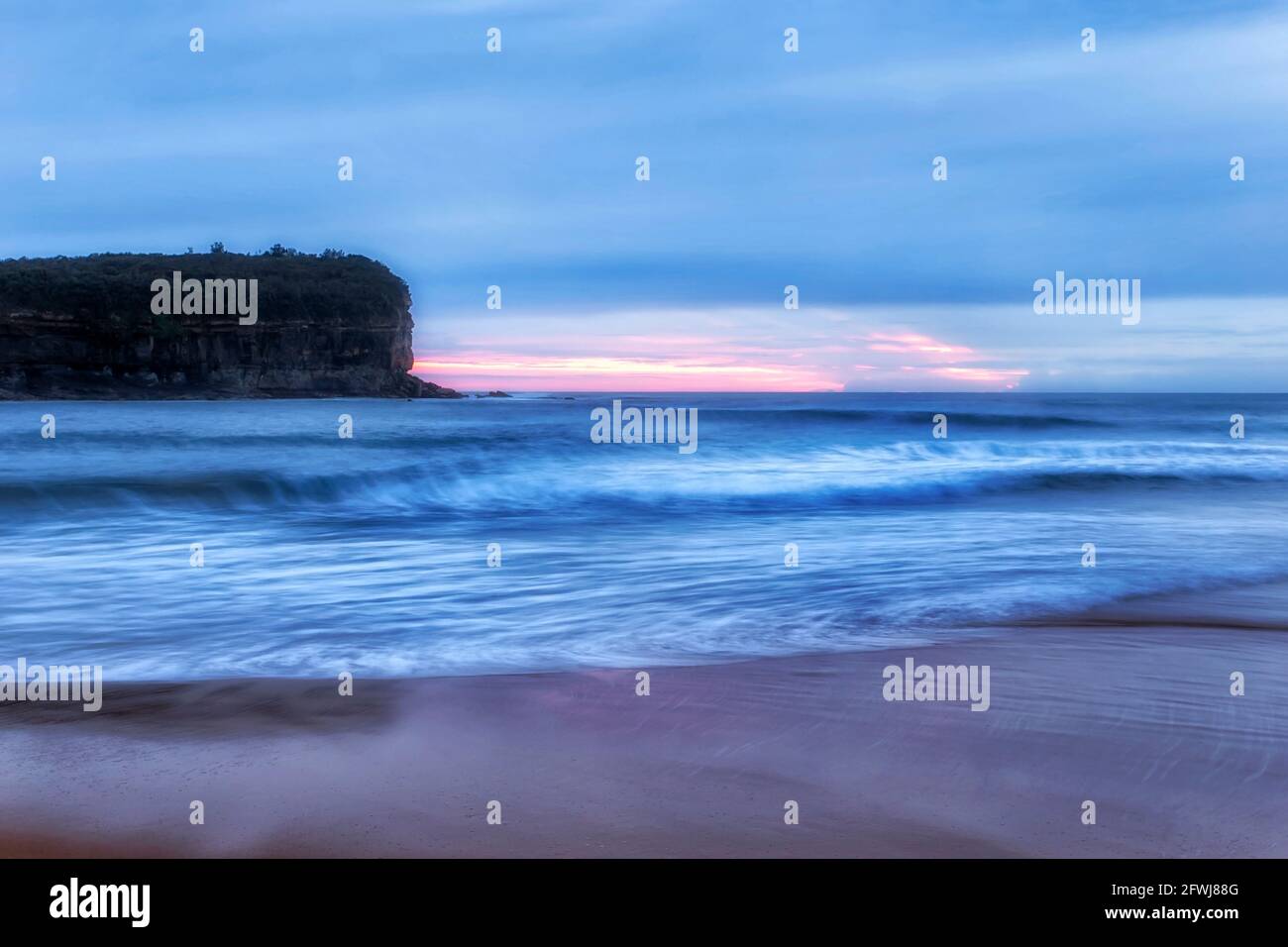 L'alba rosa dietro la punta di Mona vale sulla costa pacifica di Sydney - scenografico lungomare al largo della spiaggia di Mona vale. Foto Stock