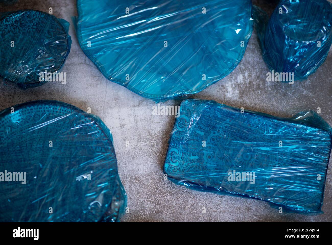 Piccole piastre avvolte in pellicola blu apposte su fondo di legno marrone. Vista dall'alto. Copia spazio. Foto di alta qualità Foto Stock