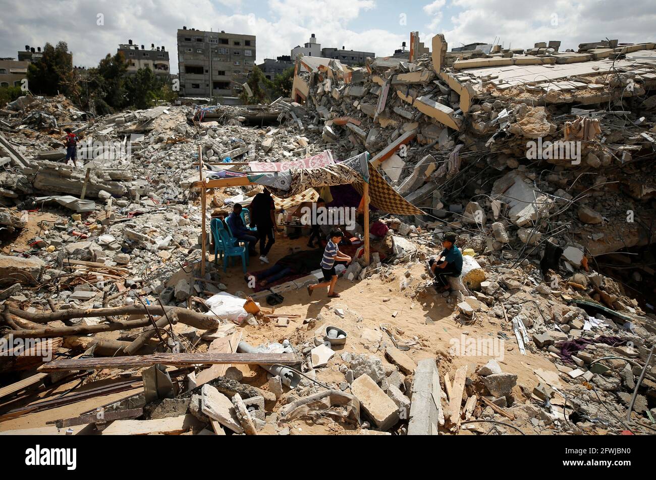 I palestinesi si siedono in una tenda di fortuna tra le macerie delle loro case distrutte dagli attacchi aerei israeliani durante i combattimenti Israele-Hamas a Gaza il 23 maggio 2021. REUTERS/Mohammed Salem Foto Stock