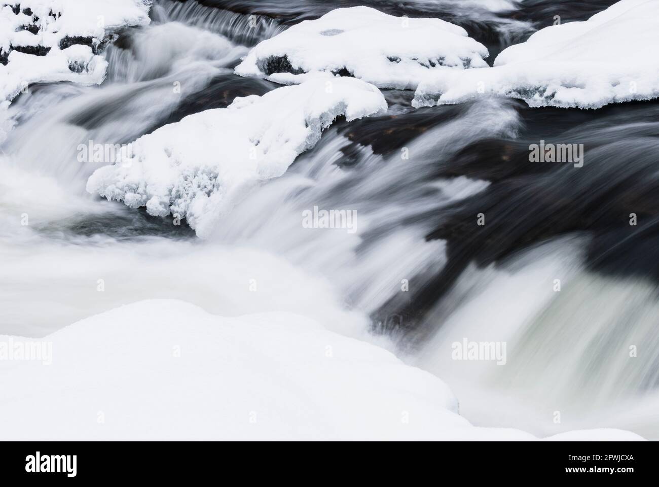 Acqua che corre sul fiume ghiacciato Foto Stock