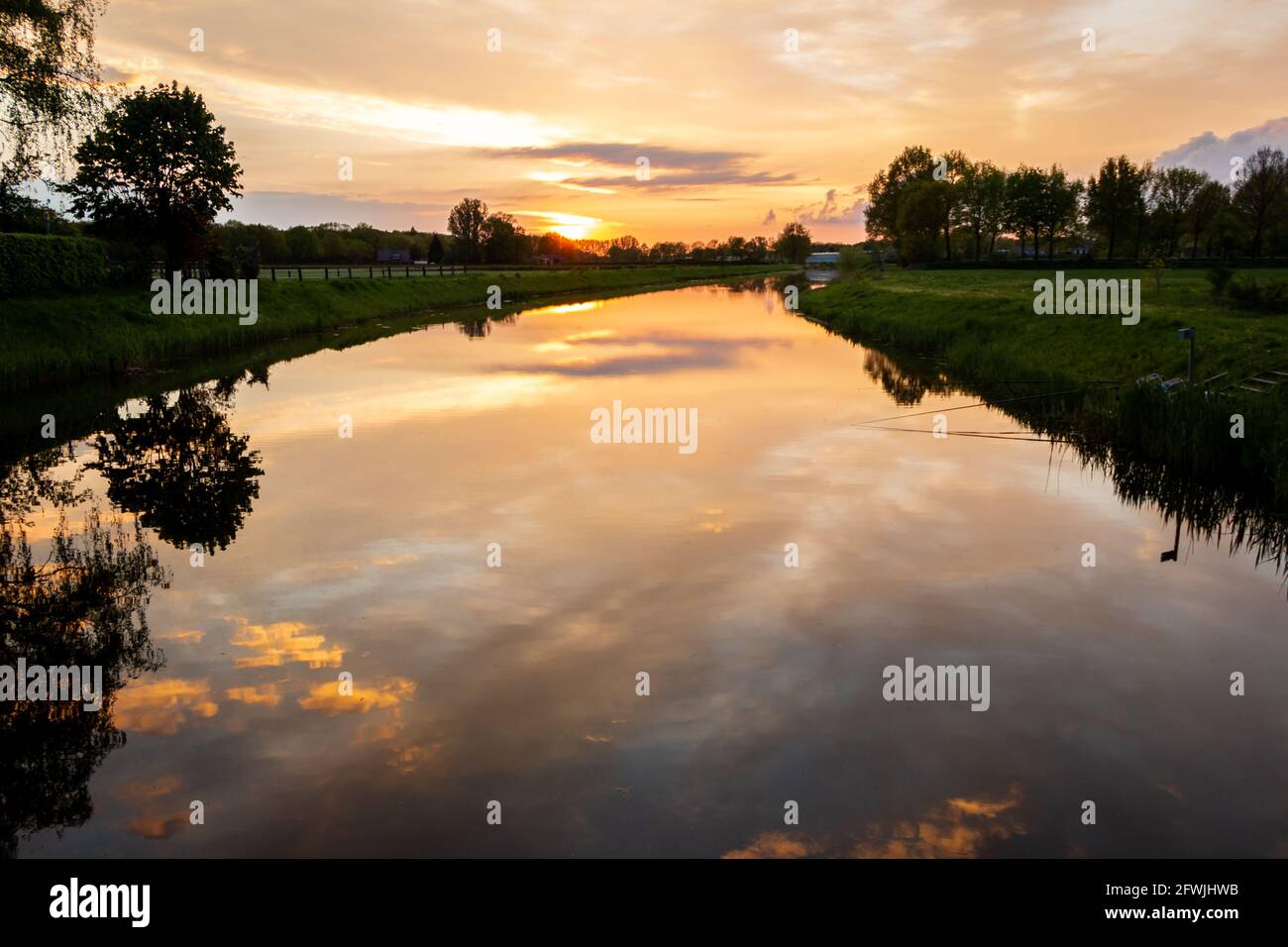Bella cornice di sole con nuvole colorate e i riflessi nell'acqua del fiume chiamato 'il Dinkel' in viola, magenta, giallo, arancione e blu Foto Stock