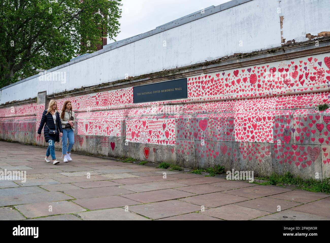 National Covid Memorial Wall in una giornata di lavoro a Lambeth, Londra, Regno Unito. Cuori rossi disegnati su un muro che rappresenta ogni morte di COVID 19. Persone Foto Stock