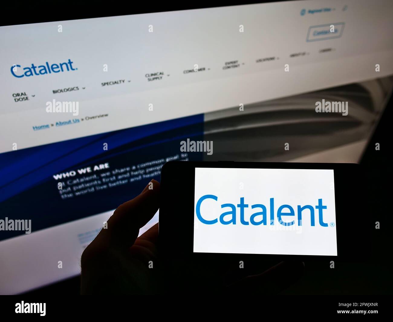 Persona che tiene lo smartphone con il logo della società farmaceutica americana Catalent Inc. Sullo schermo davanti al sito Web. Mettere a fuoco il display del telefono. Foto non modificata. Foto Stock