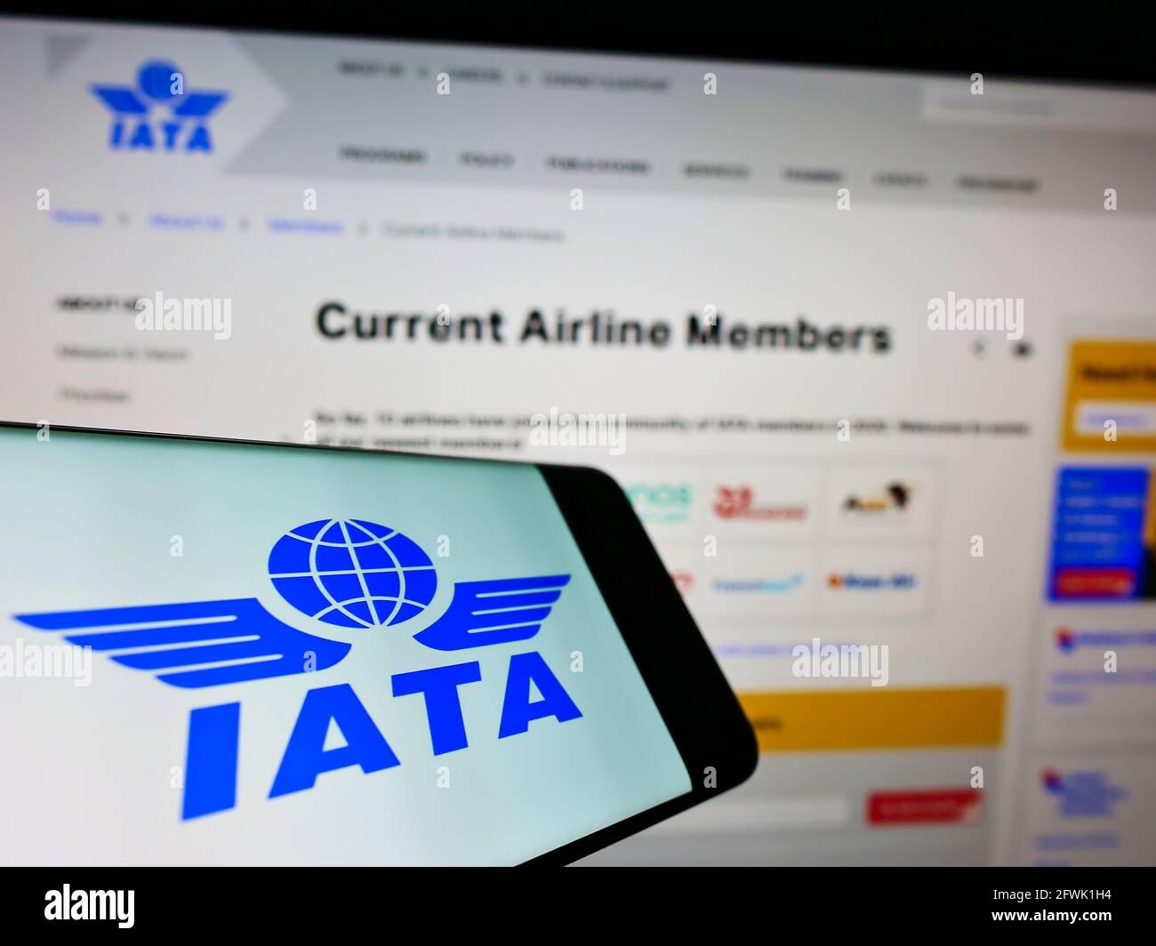 Telefono cellulare con logo della International Air Transport Association (IATA) sullo schermo davanti al sito web. Mettere a fuoco il centro-destra del display del telefono. Foto Stock