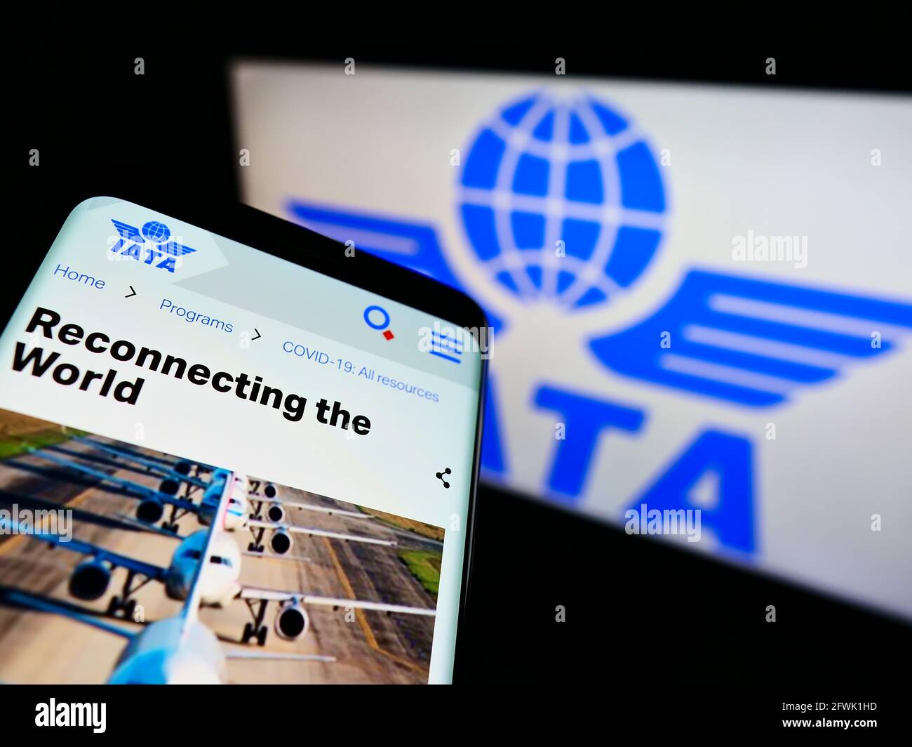Telefono cellulare con sito web della International Air Transport Association (IATA) sullo schermo davanti al logo. Mettere a fuoco in alto a sinistra del display del telefono. Foto Stock