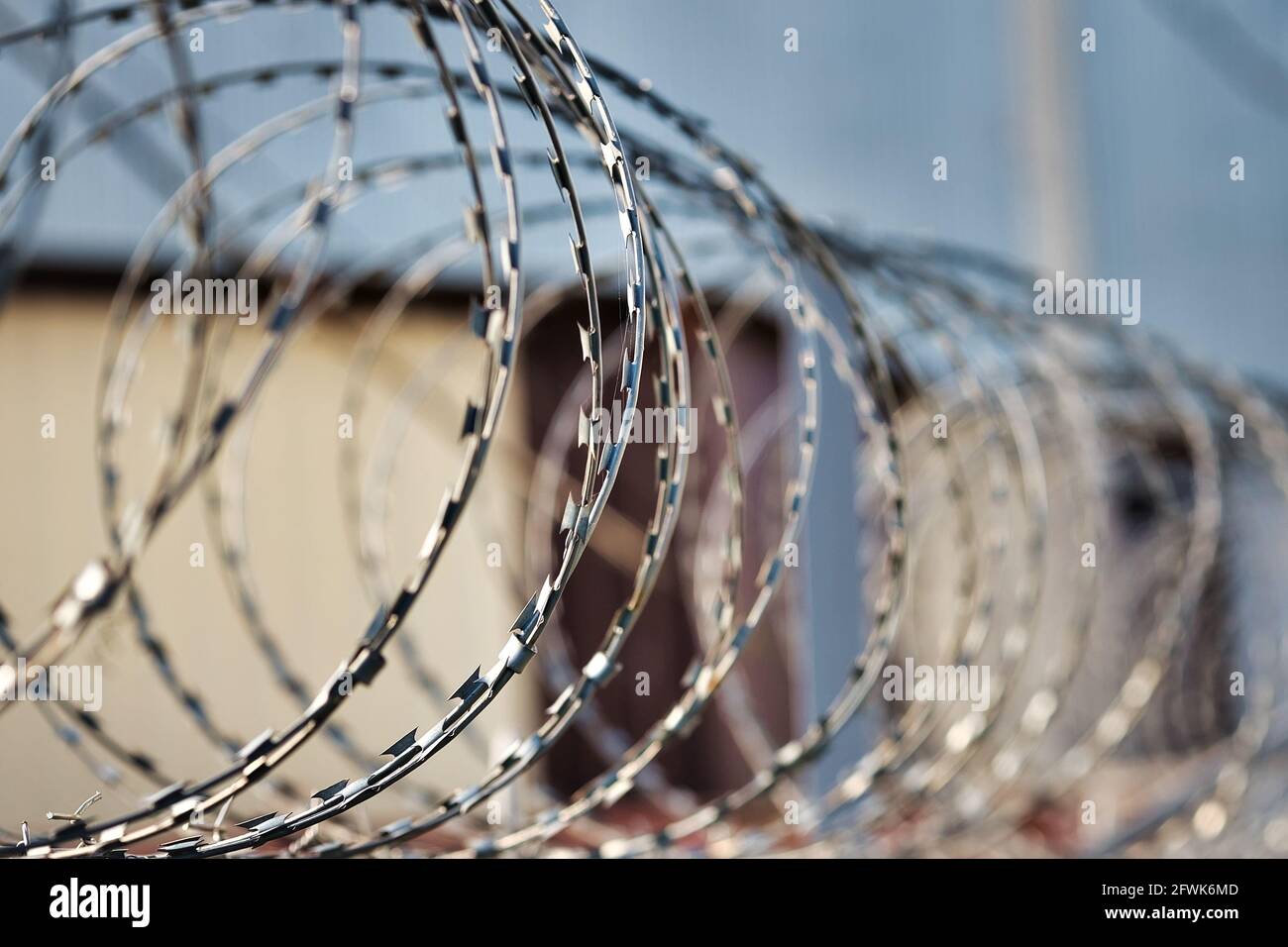 Spirali di filo spinato su una recinzione di cemento. Un simbolo di incarcerazione e di mancanza di libertà. Punizione per un crimine. Foto Stock