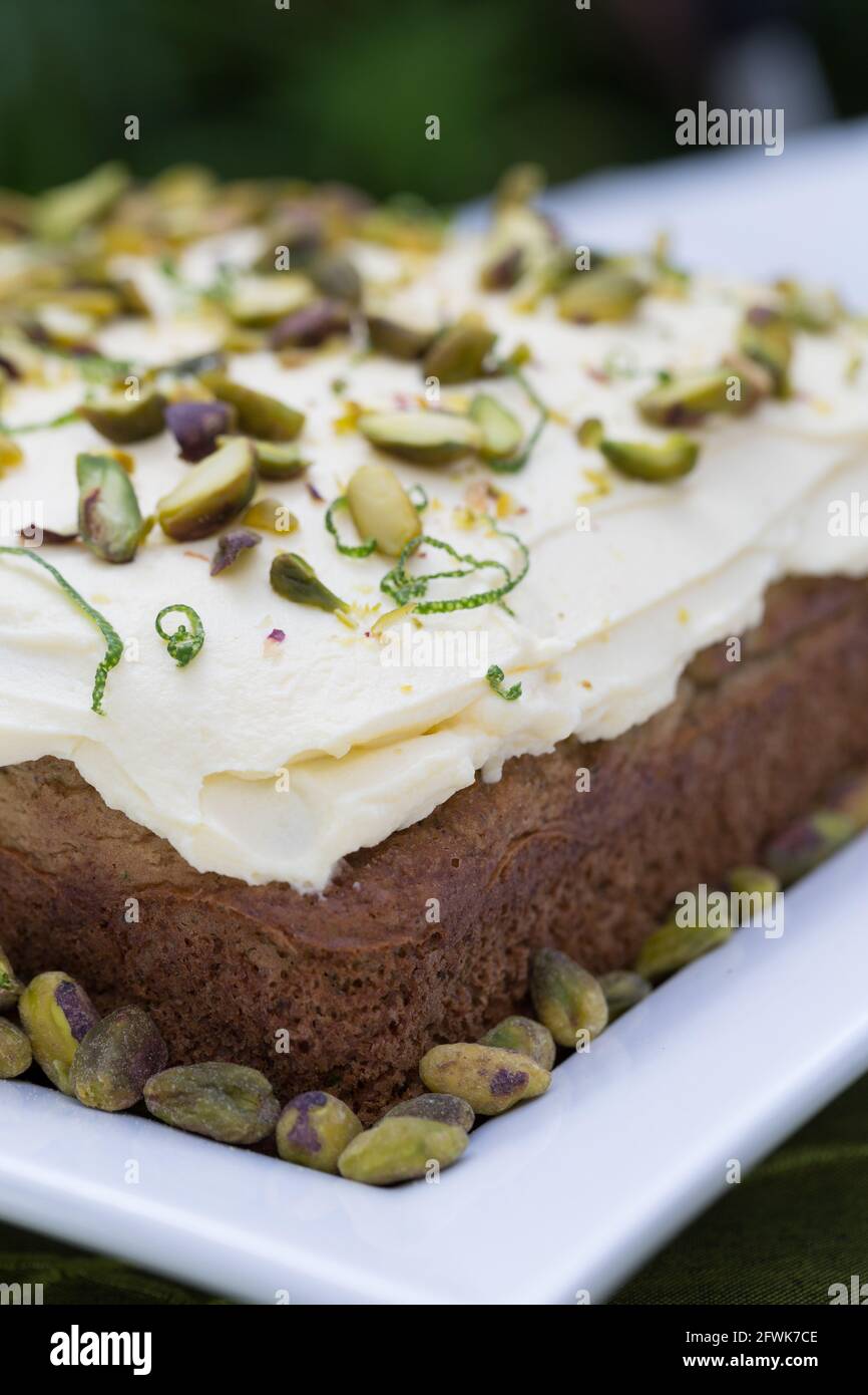 Torta di lime e passionfruit in tavola da giardino rivestita con pistacchi Foto Stock