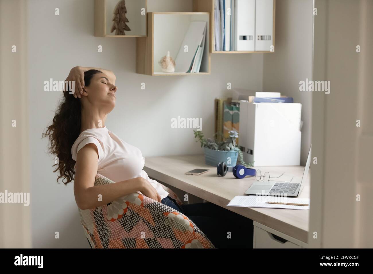 Donna latina millenaria rilassata godendo del tempo di pausa in ufficio domestico. Foto Stock