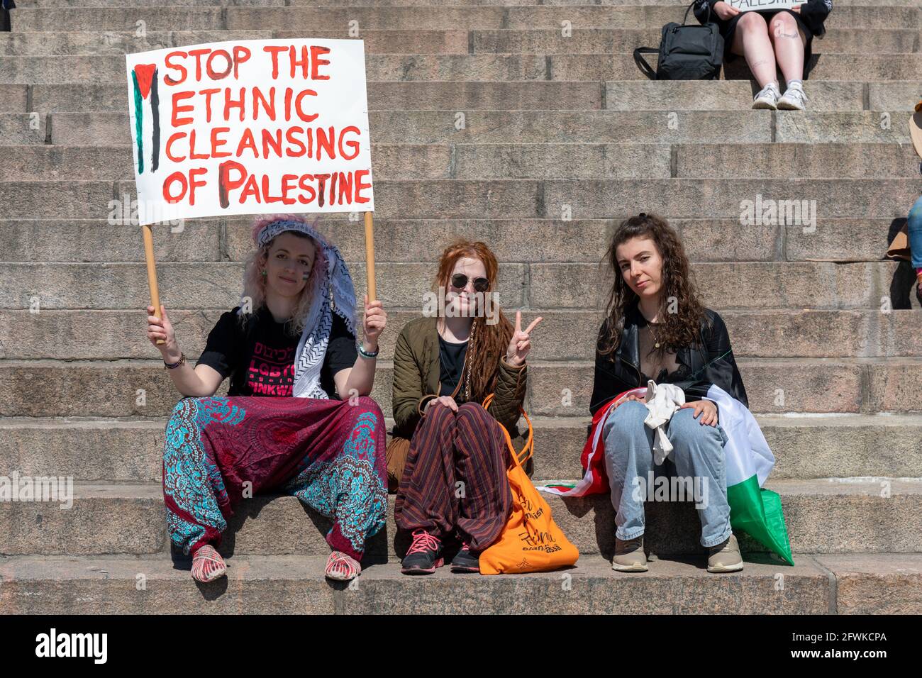 Tre donne manifestanti con un cartello a nome della Palestina seduti sulla scalinata della Cattedrale di Helsinki a Helsinki, in Finlandia Foto Stock