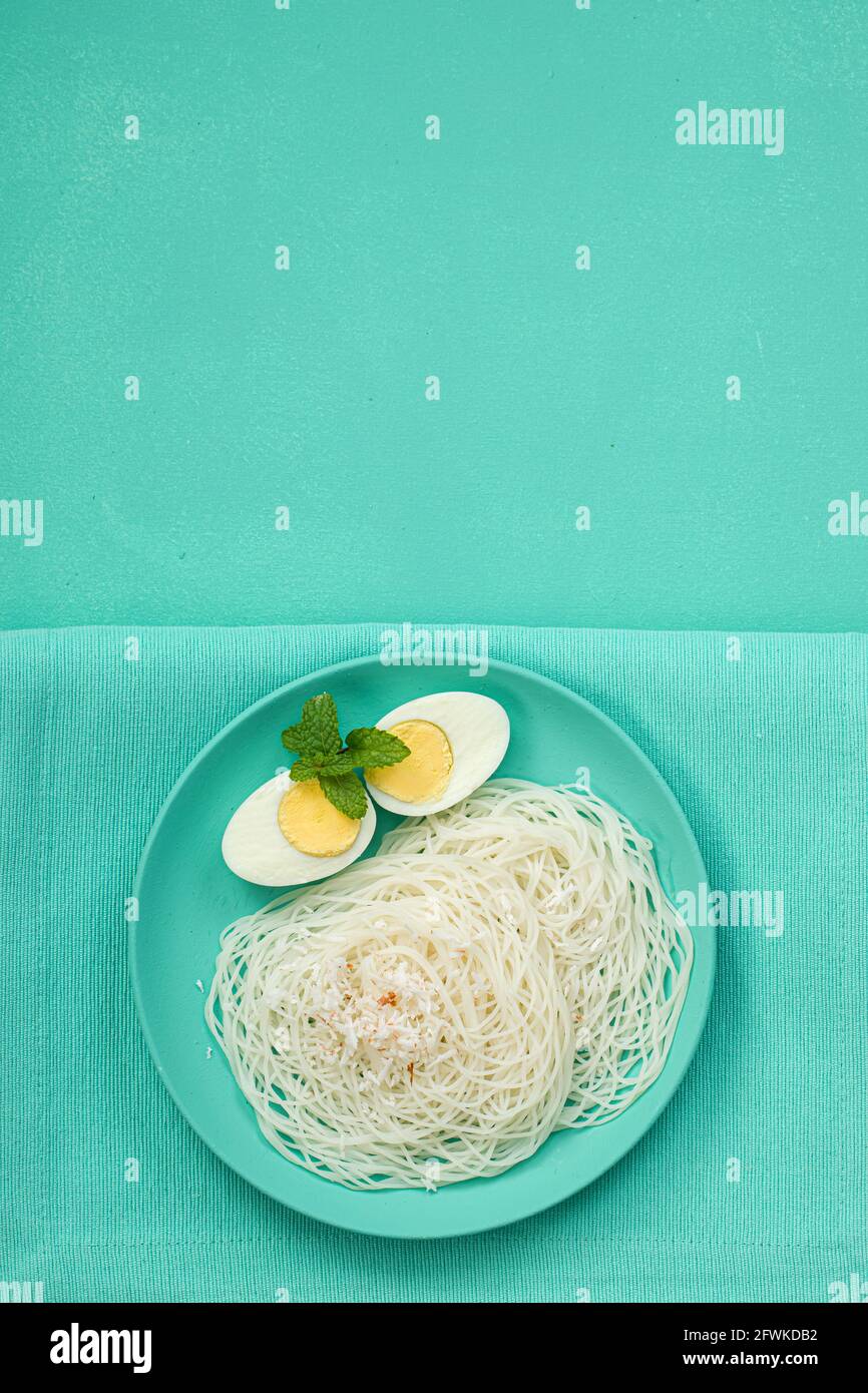 Ideyappam o noolappam, colazione indiana del sud che è organizzato splendidamente con due fette di uova bollite di colore acquamarina stoviglie pla Foto Stock