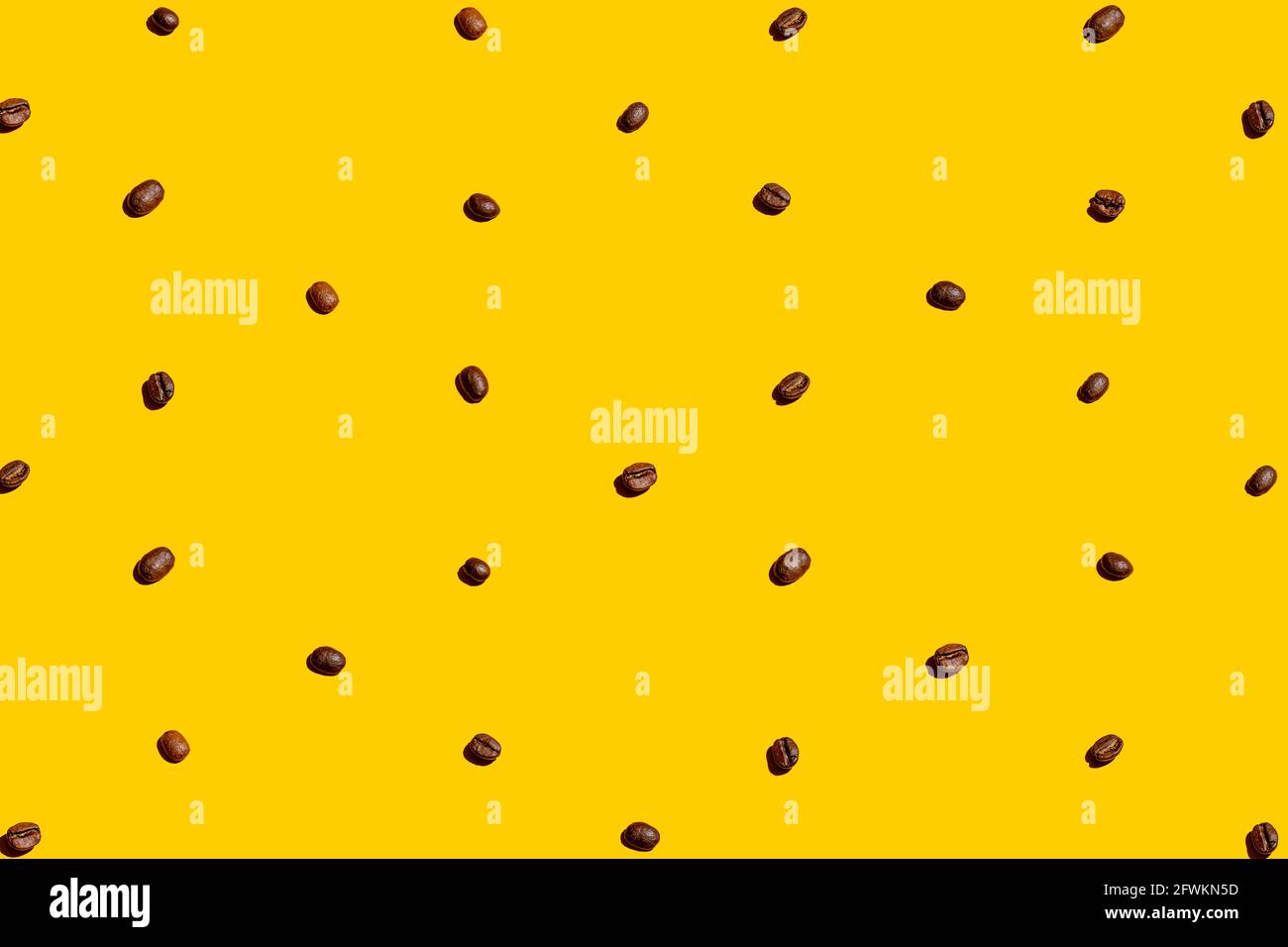 I chicchi di caffè sono organizzati e formano una consistenza su sfondo giallo. Foto Stock