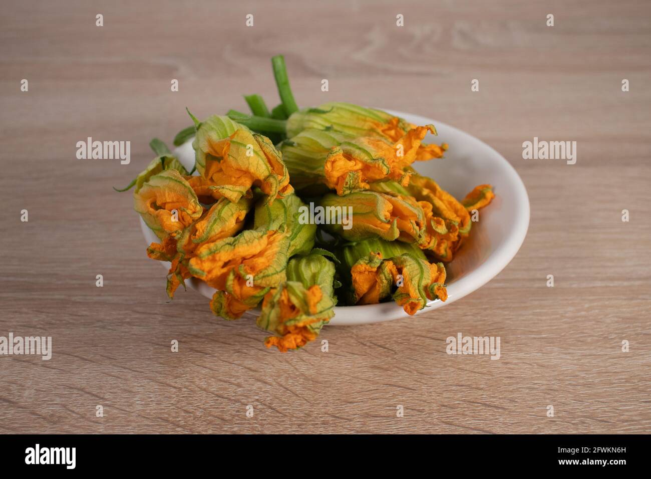 Mazzo di fiori di zucca freschi su una piccola ciotola. Fiori d'arancio. Ingrediente fresco grezzo. Foto Stock