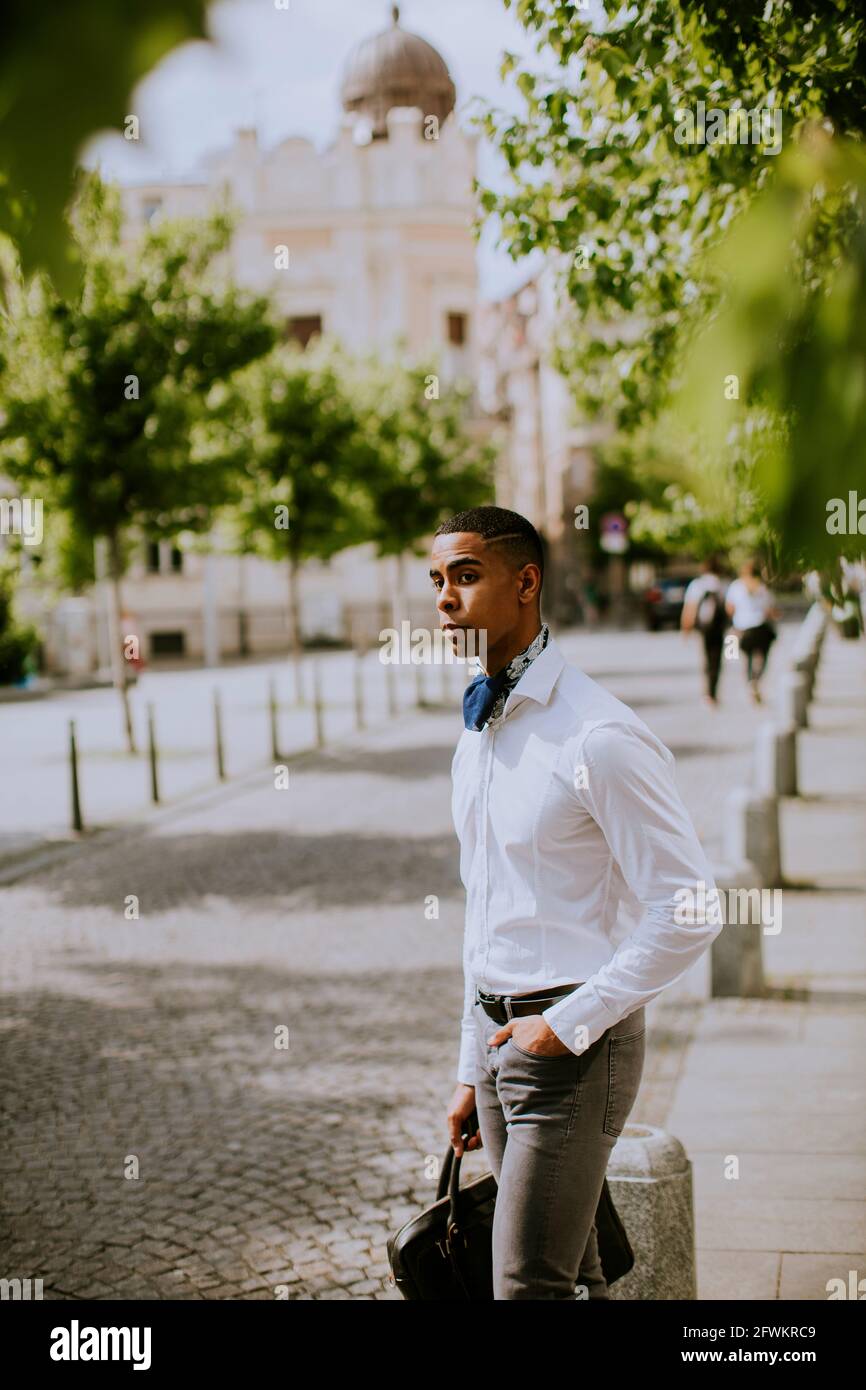 Bel giovane uomo d'affari afro-americano in attesa di un taxi su un via Foto Stock