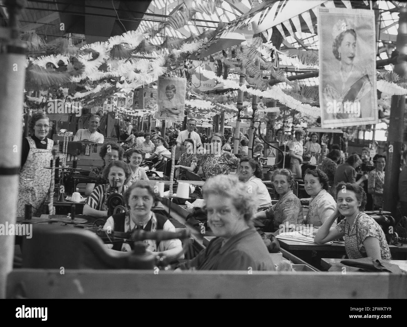 1953, storico, lavoratori femminili - e alcuni datori di lavoro maschili - sul pavimento della fabbrica guardare la macchina fotografica a Hepworths, Leeds, Queen's Coronation, Inghilterra, Regno Unito. Una foto di sua Maestà la Regina Elisabetta II è appesa al soffitto della fabbrica. Foto Stock