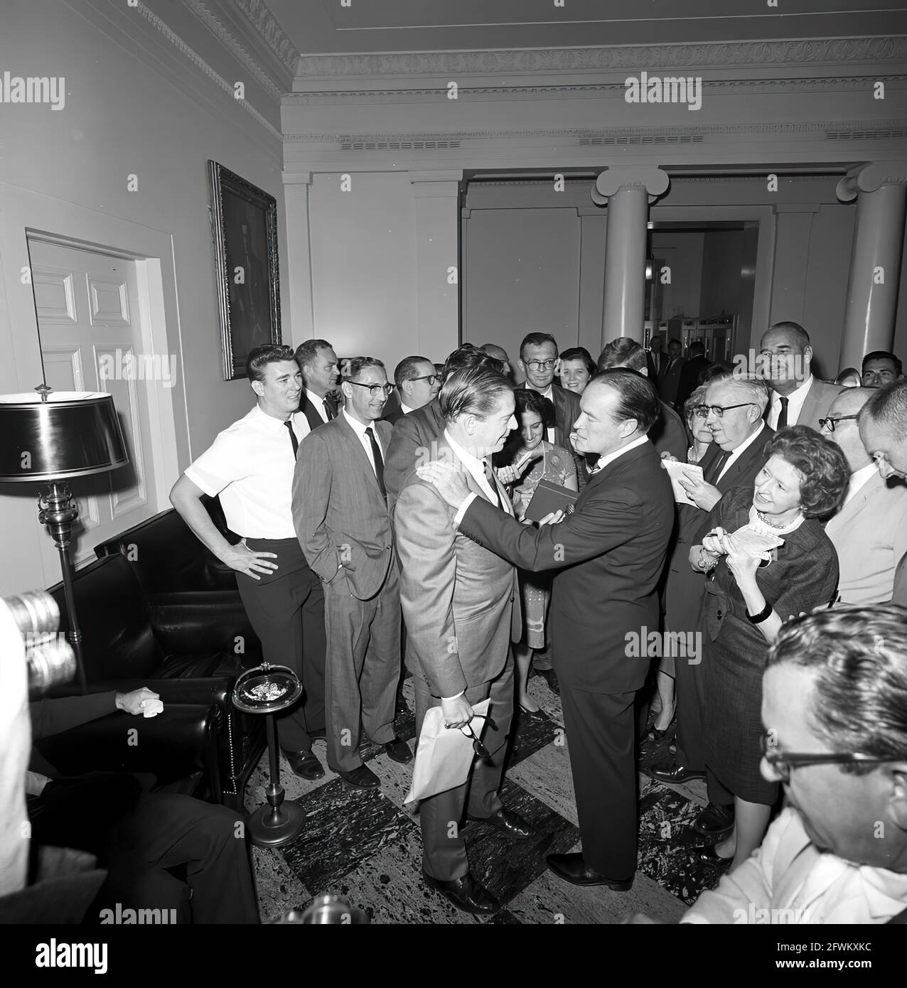 L'attore e comico, Bob Hope, si reca in visita con il comico Milton Berle, dopo la cerimonia di presentazione della medaglia d'oro al Congresso di Hope; ha ricevuto la medaglia dal presidente John F. Kennedy in riconoscimento dei suoi servizi nel paese come intrattenitore durante la seconda guerra mondiale I giornalisti osservano, compreso il corrispondente della Casa Bianca per United Press International (UPI), Helen Thomas (in piedi al centro, tra il Sig. Berle e il Sig. Hope), e il corrispondente della Casa Bianca per la Washington Star, Garnett D. Horner (in piedi a destra, dietro il Sig. Hope). Foto Stock