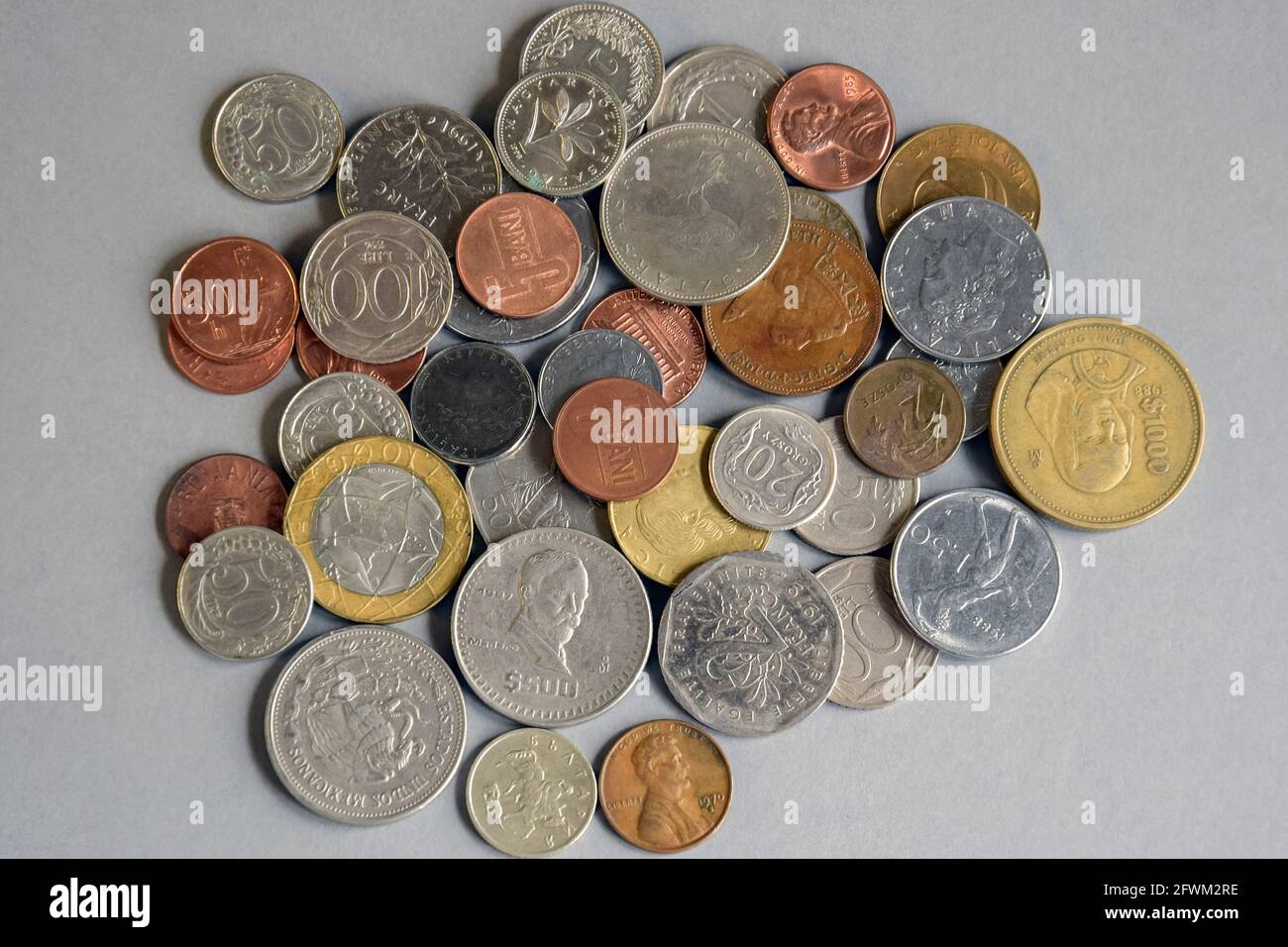 Monete di paesi diversi e denominazioni su sfondo grigio. Contanti. Raccolta di monete e numismatica. Concetto di investimento, cambio valuta Foto Stock