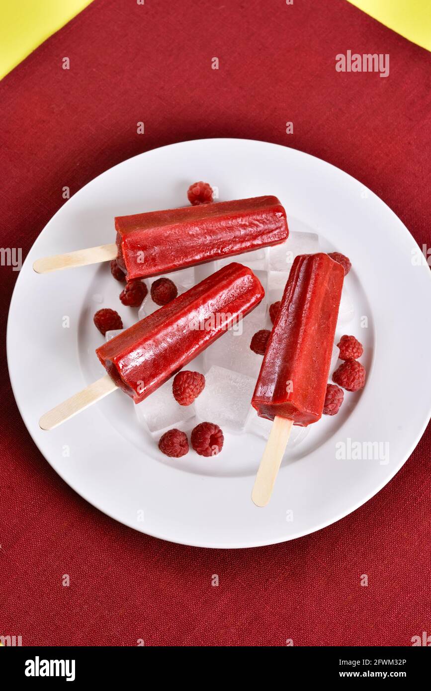 Il gelato al lampone viene affoltato su un piatto bianco. Gustoso dessert estivo. Foto Stock