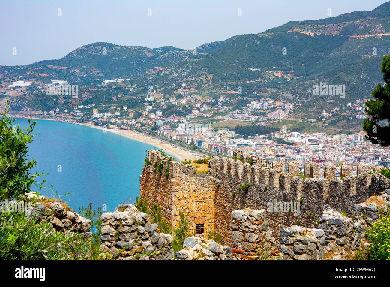 Splendida vista sulla città di Alanya dall'alto. Un antico muro difensivo sepolto in alberi verdi e una località di villeggiatura circondata da un mare blu su uno si Foto Stock