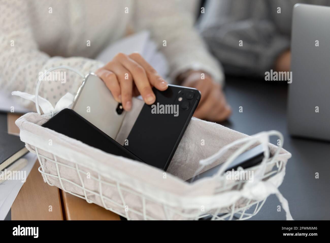 Primo piano donna ritagliata mettendo il telefono nel cestino, nessun cellulare Foto Stock