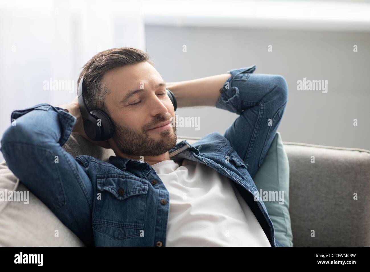 Gioioso uomo di mezza età in cuffia che ascolta la musica Foto Stock