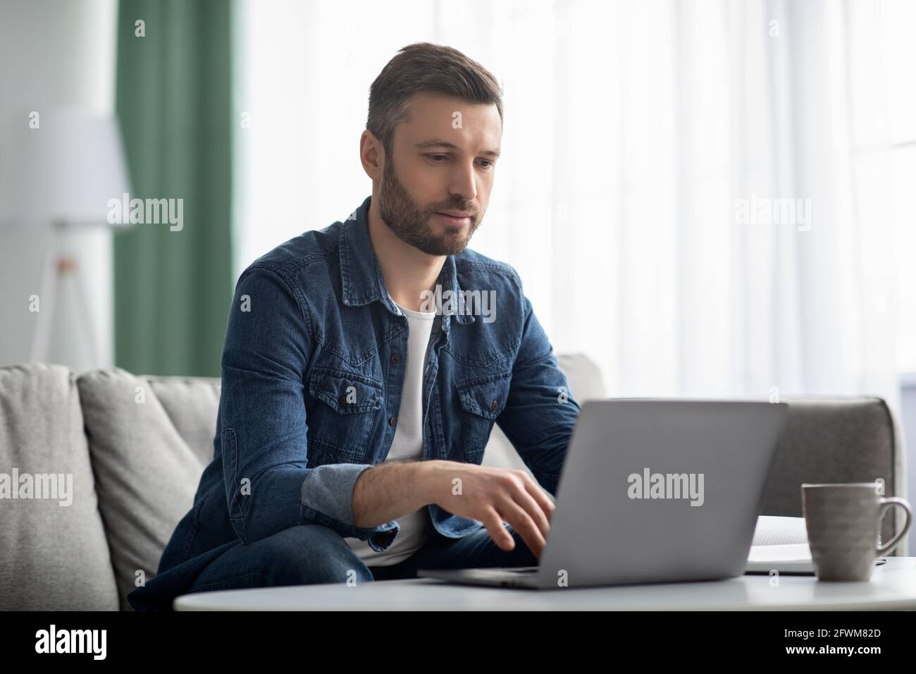 Uomo d'affari di media età che lavora da casa, utilizzando un computer portatile Foto Stock