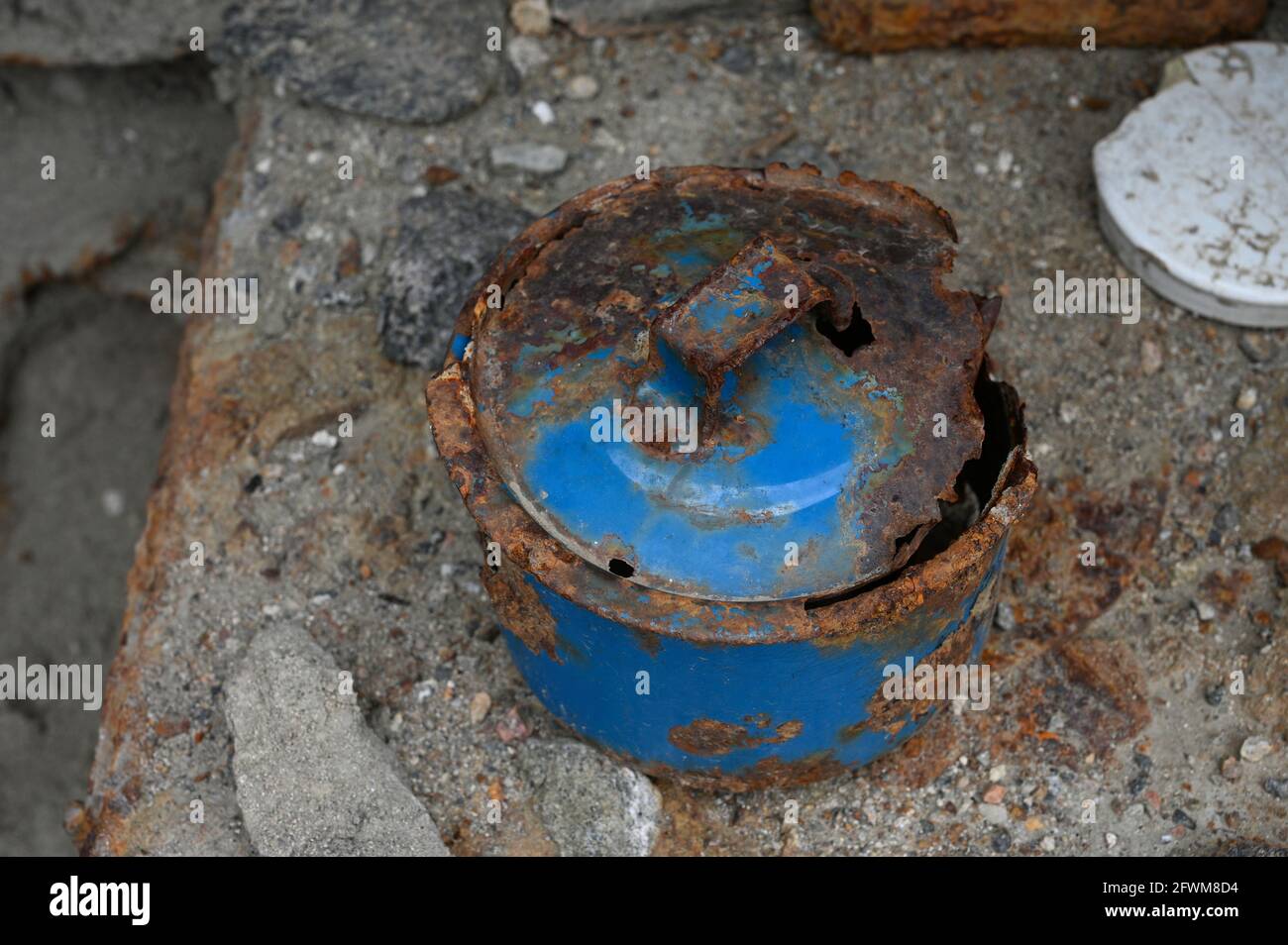 Vecchia pentola di cottura blu arrugginita, lasciata in un edificio in pietra rovinata. Molto decaduto con parti di metallo mangiate via dalla ruggine. Isolato su fondo di pietra. Foto Stock
