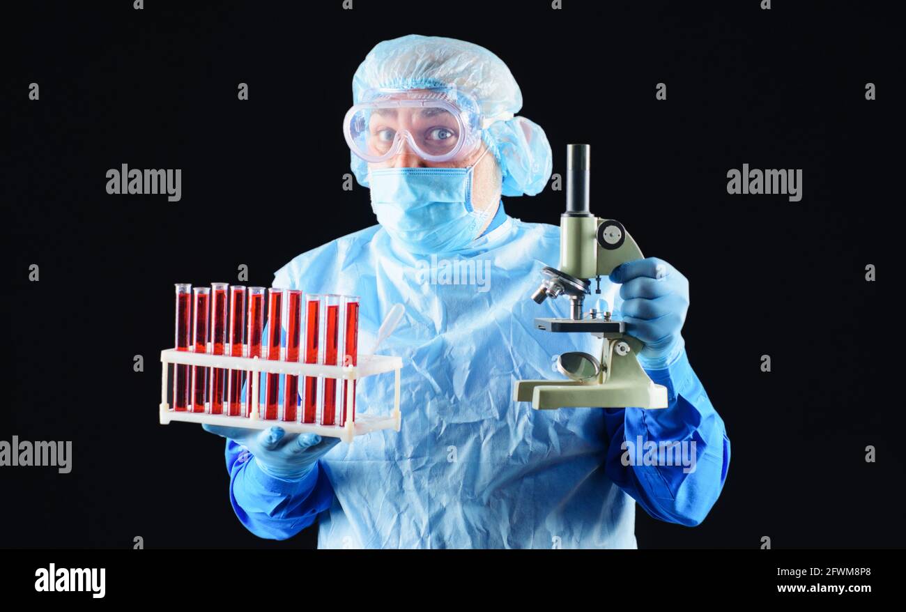 Medico con provette per analisi del sangue e microscopio. Tecnico di laboratorio che analizza il campione di sangue in clinica. Foto Stock