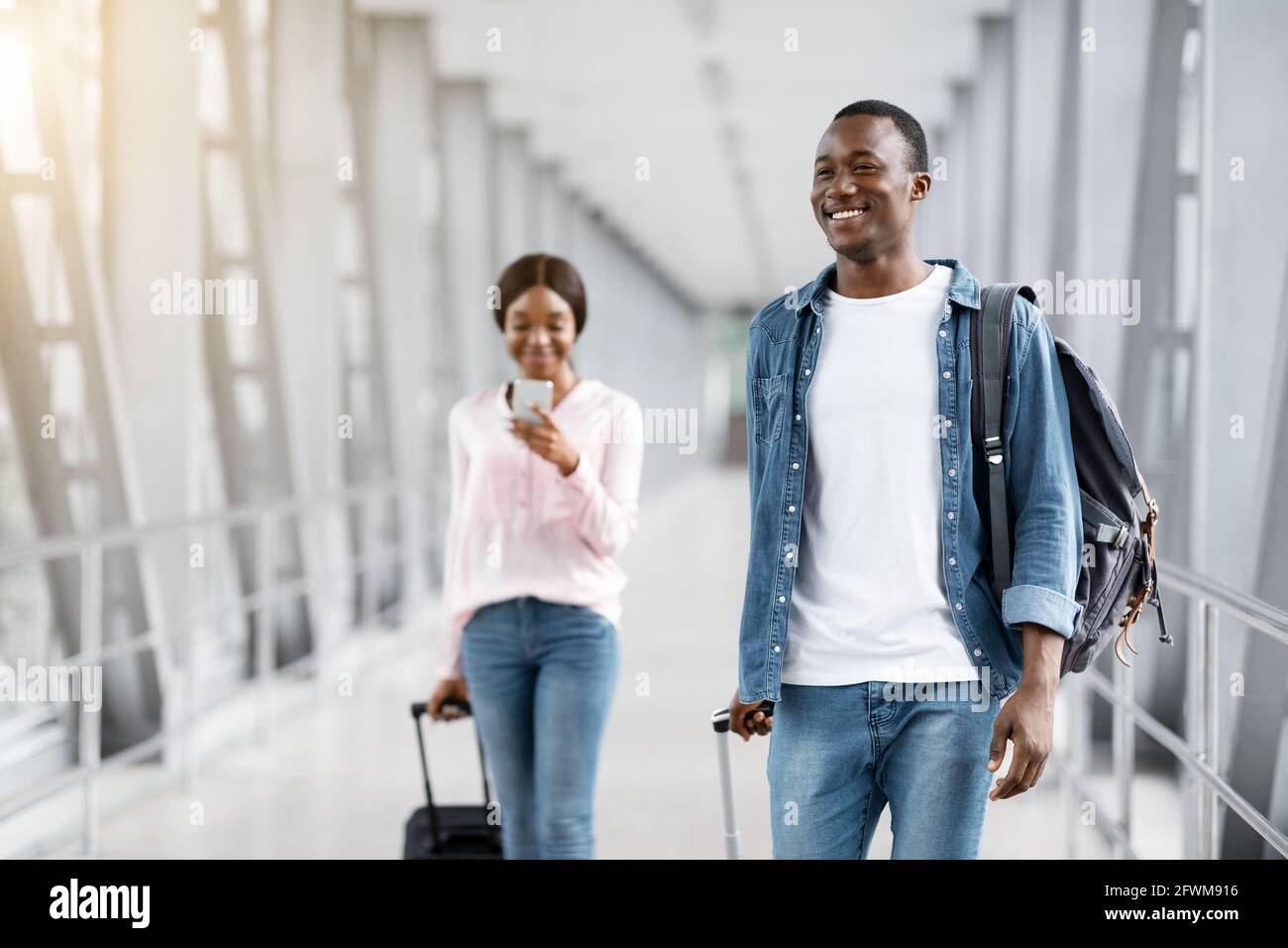 In viaggio d'aria. Happy Smiling Black People camminando con valigie nel terminal dell'aeroporto Foto Stock