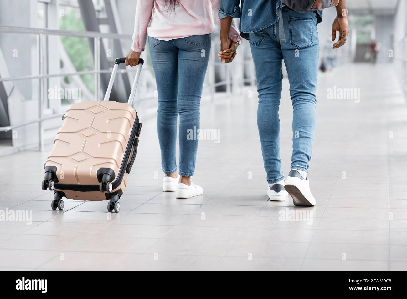 Trasporto aereo. Immagine ritagliata della coppia nera camminando con i bagagli in aeroporto Foto Stock