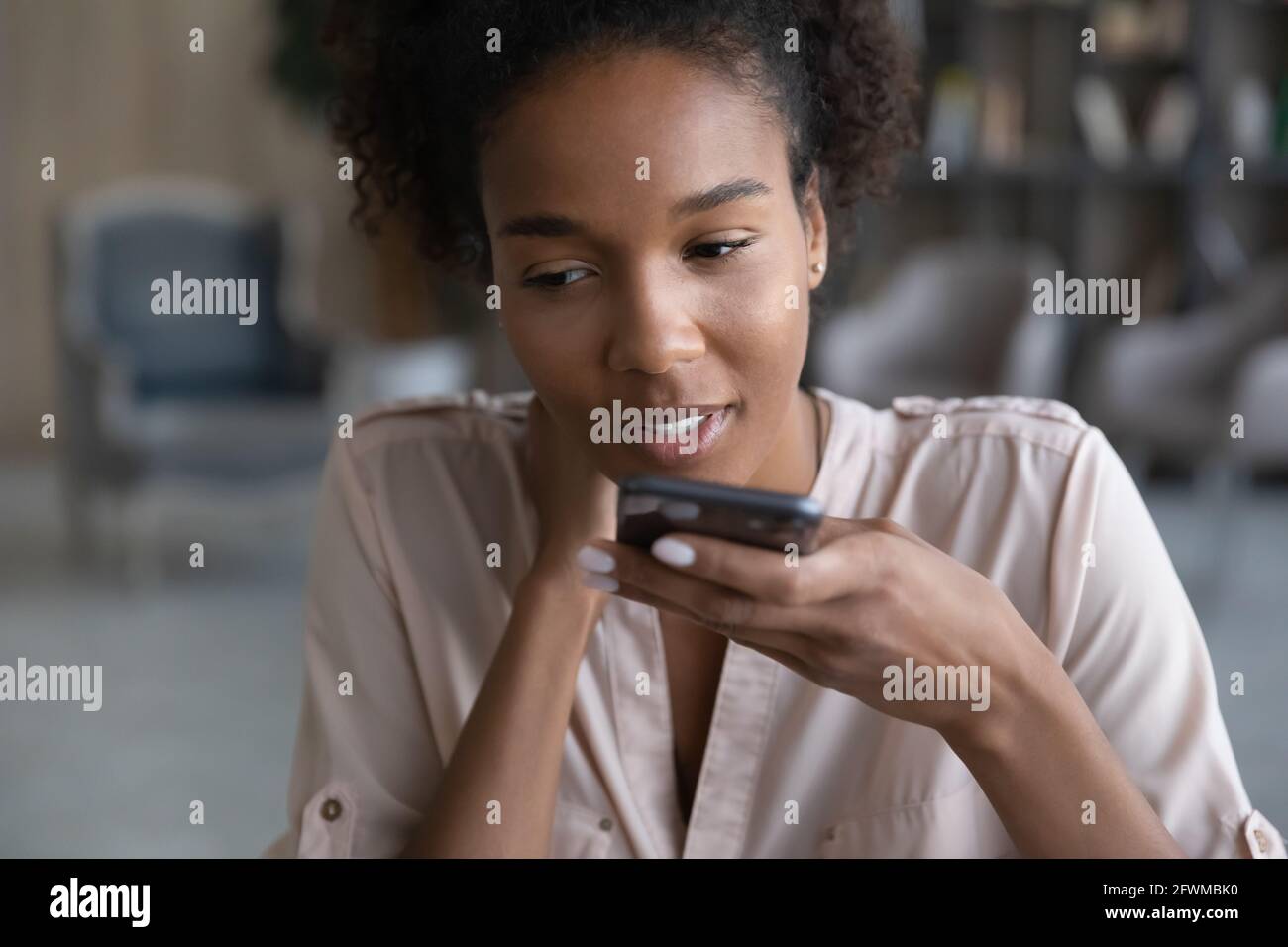 Giovane donna africana che dettava messaggio audio sul cellulare. Foto Stock